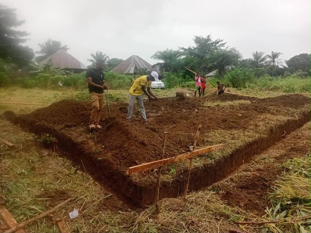 Workers digging the rectangular foundation trench for Clinic One, marked out with wooden stakes