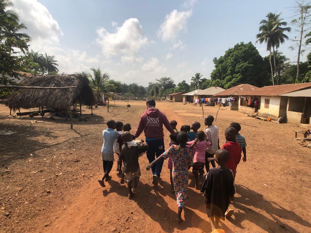Iván walking through a village in Sierra Leone with a group of children during the medical mission